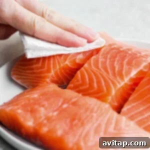 Blotting salmon dry with a paper towel.