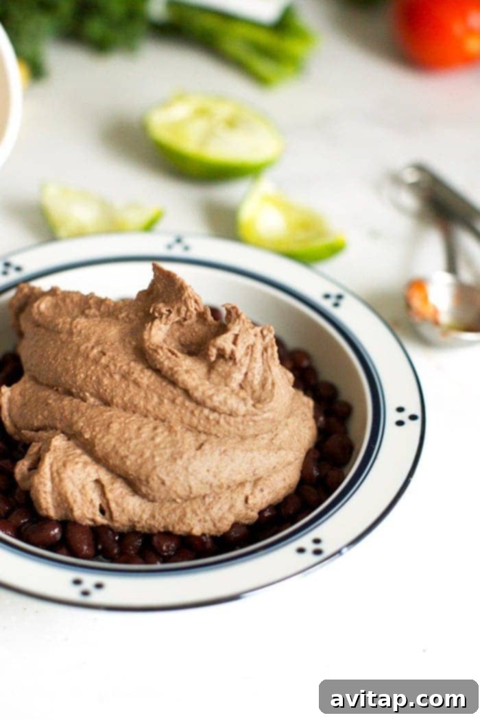 A close-up shot of Mexican Black Bean Hummus being scooped into a serving bowl, highlighting its creamy texture and rich color, ideal for a wholesome and tasty snack.