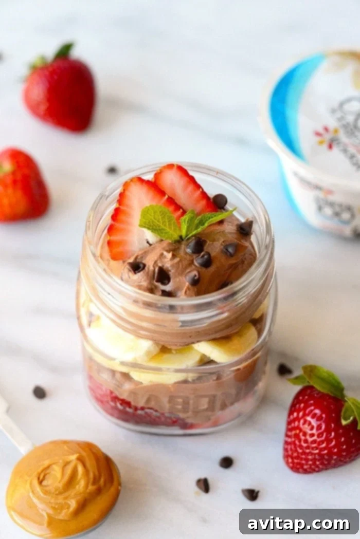 Mousse Parfait in Jar Healthy chocolate peanut butter mousse parfait elegantly presented in a tall mason jar, garnished with berries