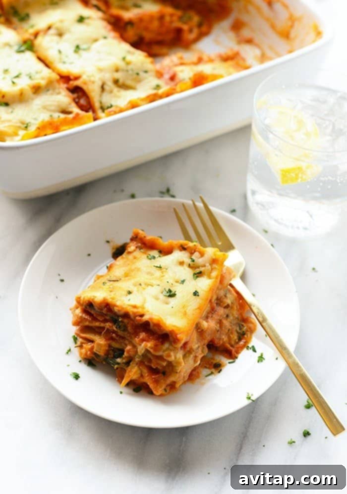 A perfectly portioned slice of golden-baked sweet potato lasagna on a white plate, showcasing its layers of noodles, creamy filling, and vibrant vegetables.