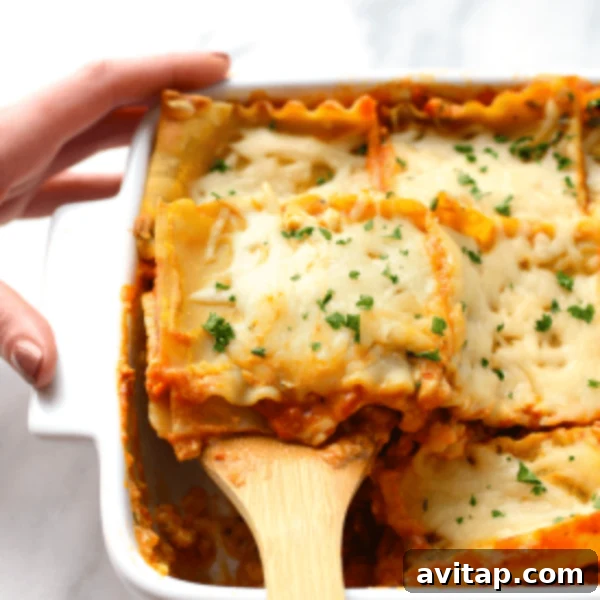 Hearty Sweet Potato Lasagna baked in a white casserole dish, served with a wooden spoon.