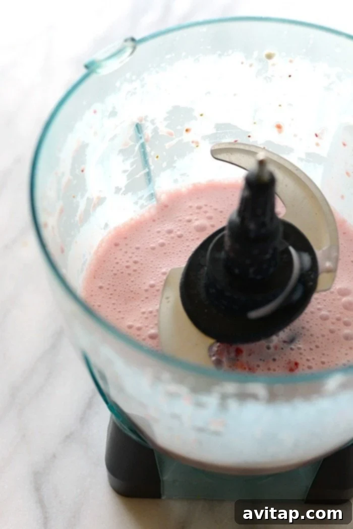 Smooth Strawberry Puree for Overnight Oats The blended strawberry mixture in a food processor, ready to be combined with oats.