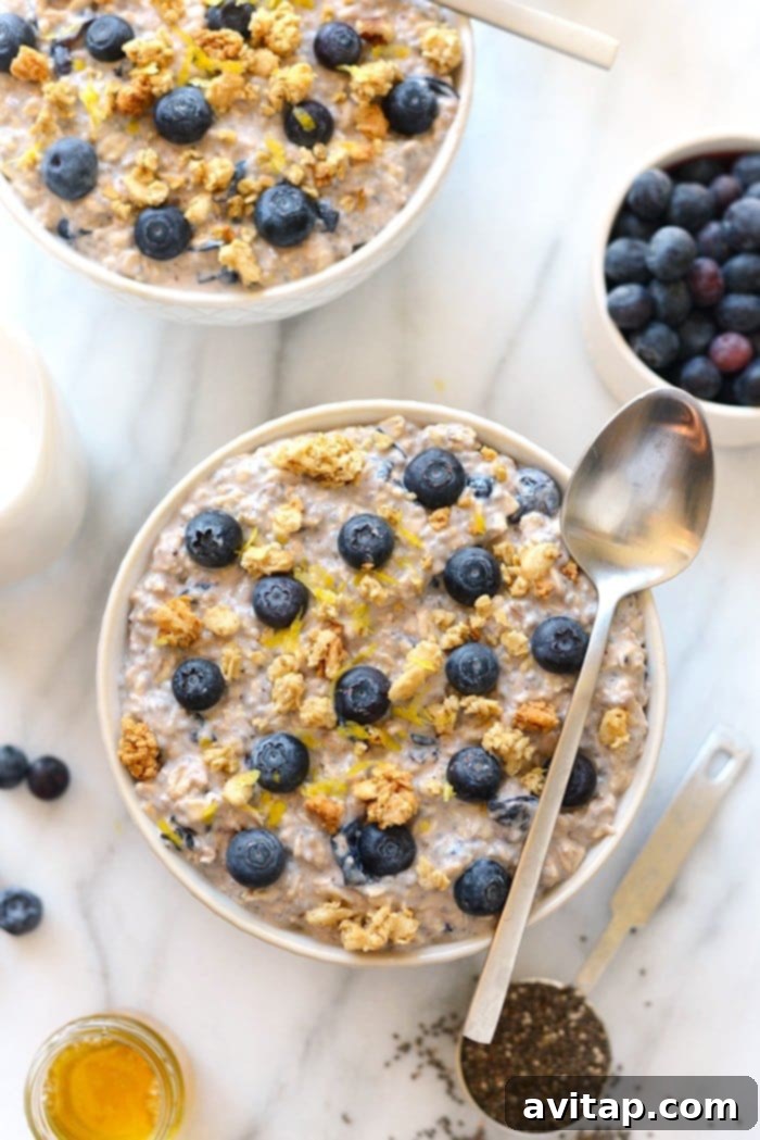 Enjoy a vibrant and healthy breakfast with this bowl of blueberry overnight oats. A glass bowl filled with blueberry overnight oats, topped with fresh blueberries, granola, and lemon zest.