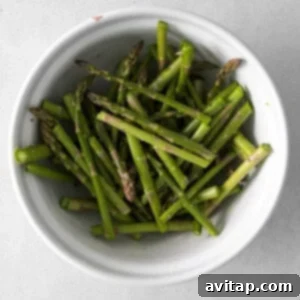 Crispy Air Fryer Asparagus 9 Asparagus spears being tossed with seasonings in a bowl.