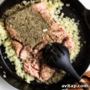 A cast iron skillet filled with ground turkey, herbs, and spices.