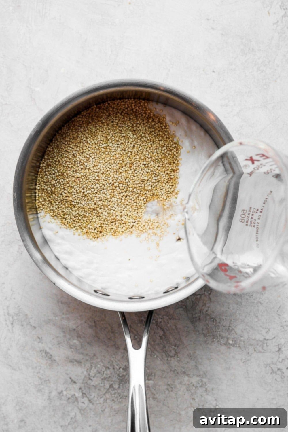 Island Coconut Quinoa 3 Uncooked quinoa being combined with rich coconut milk and water in a saucepan, a delightful starting point for the recipe.