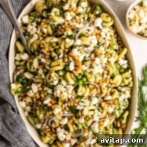 A vibrant bowl of lemon pasta salad ready to serve, garnished with herbs and feta.