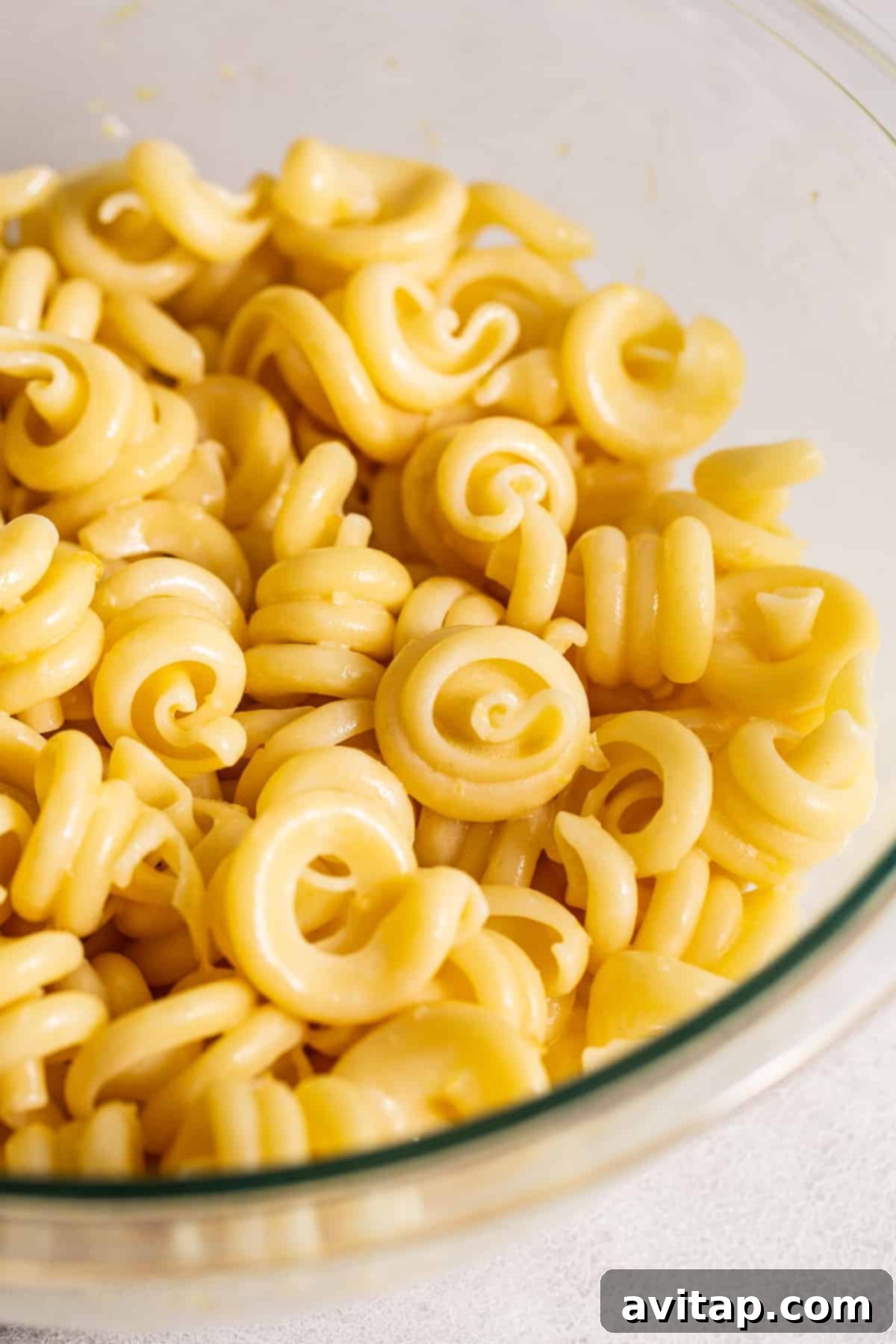 Close-up of al dente pasta noodles in a mixing bowl, perfectly cooked and ready for the vibrant dressing and fresh add-ins.