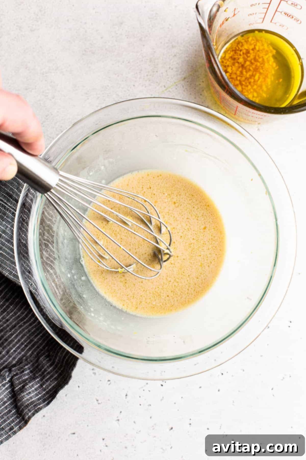 Close-up of the creamy and zesty garlic lemon dressing being whisked in a bowl, showcasing its smooth texture.