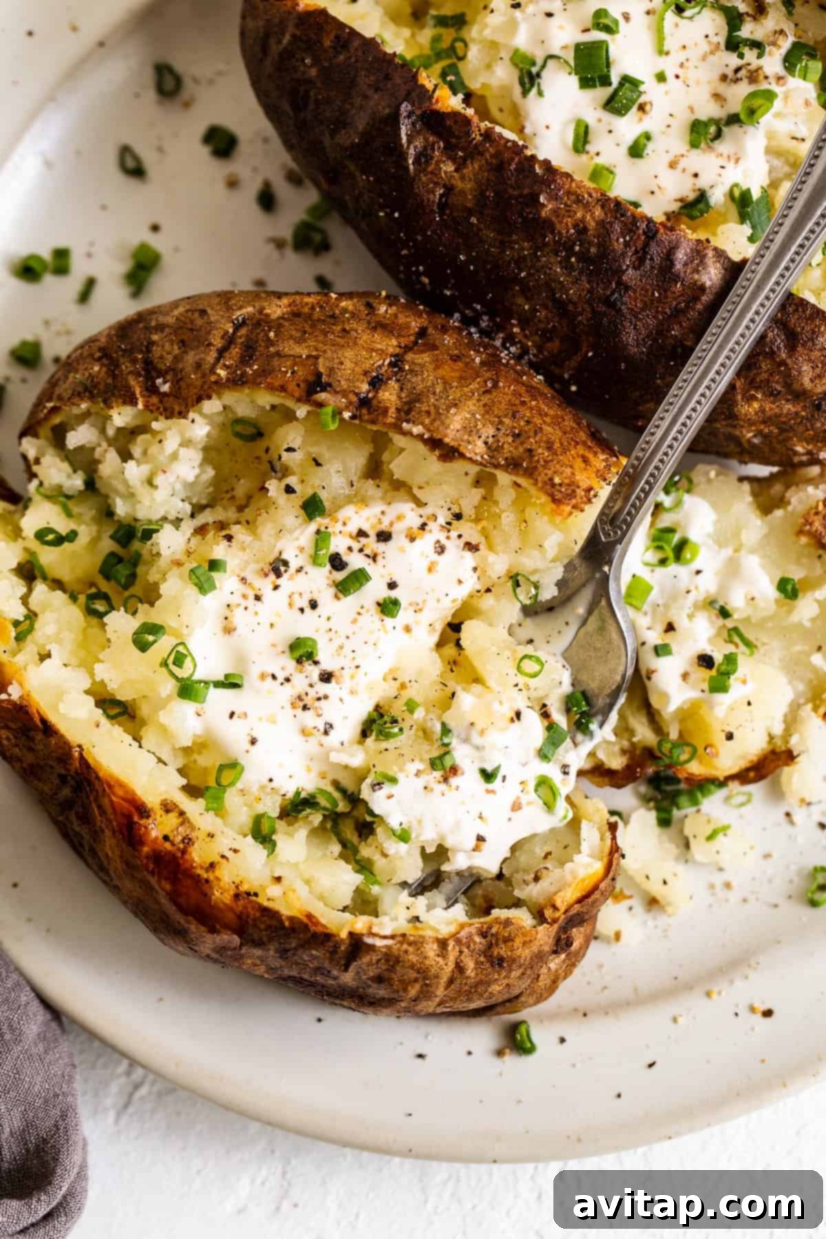 Freshly cooked air fryer baked potatoes, split open and ready for toppings.