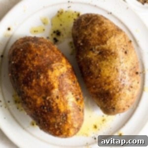 Two roasted potatoes on a white plate, seasoned with salt, pepper, and garlic powder.