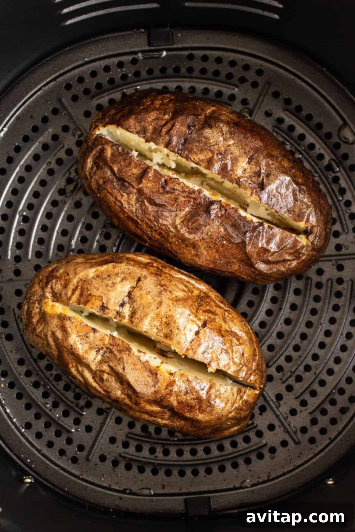 Beautifully baked potato in an air fryer basket, showing its crispy skin