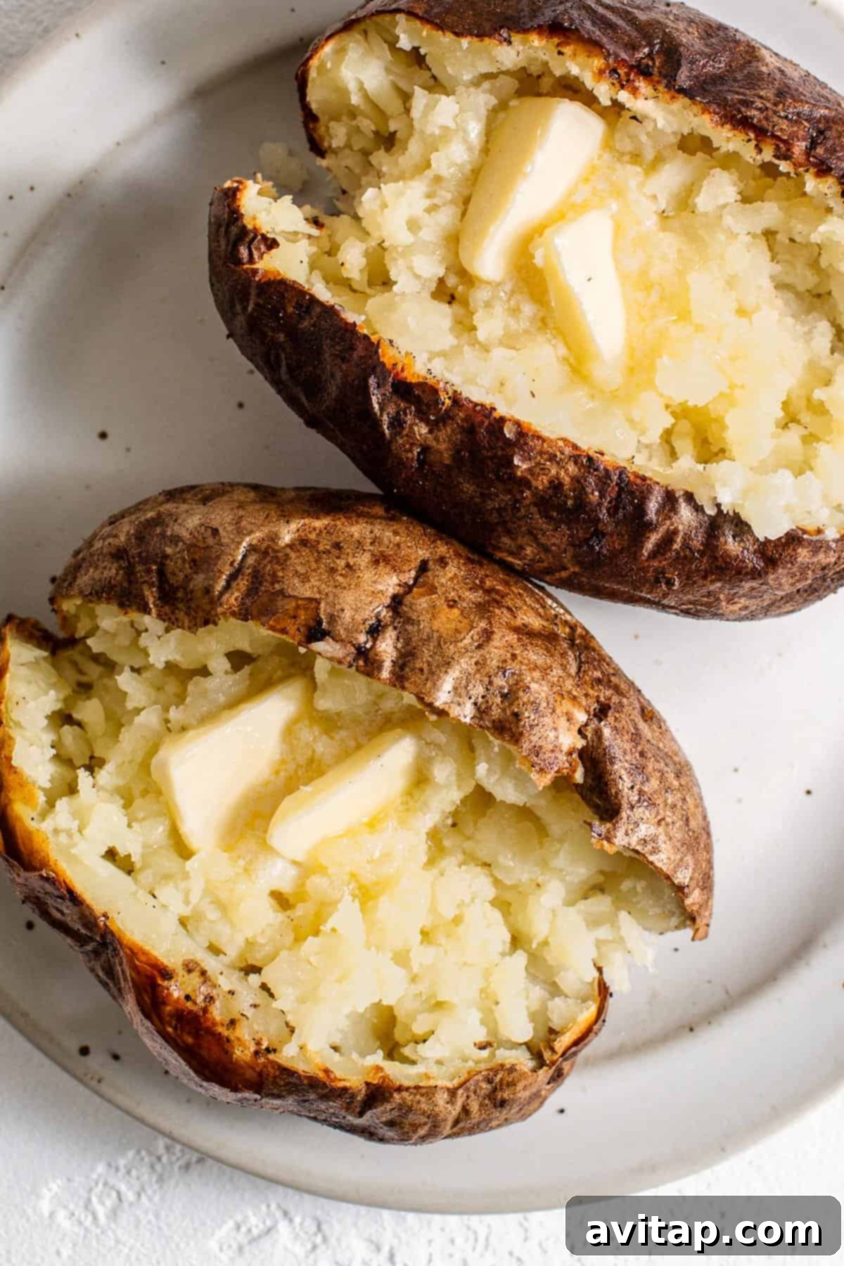 Close-up of a baked potato with a pat of melting butter on top, ready to be enjoyed.