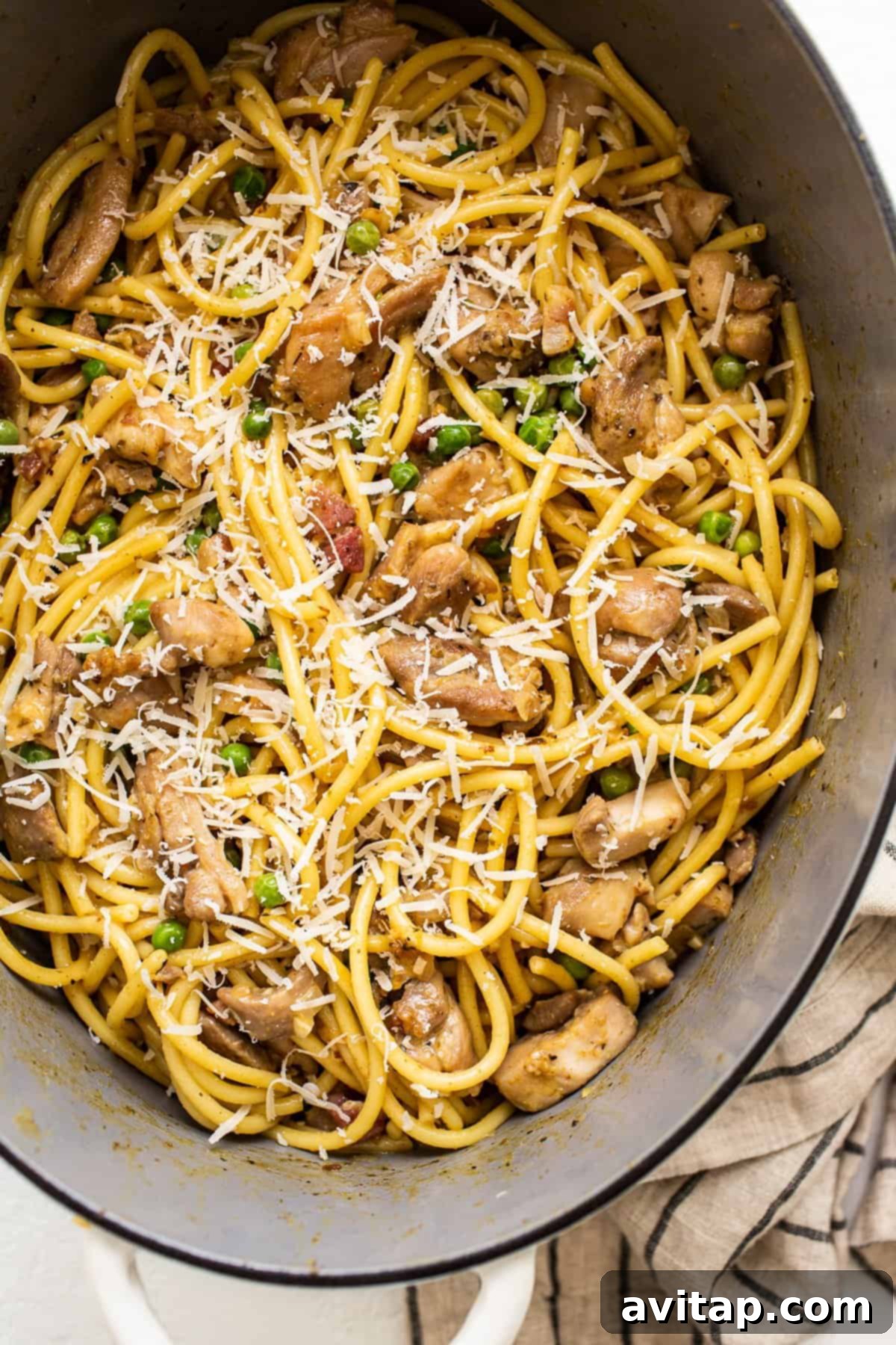 Chicken carbonara in a Dutch oven, topped with freshly shredded Parmesan cheese.