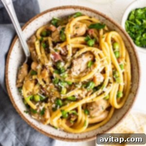 A bowl of pasta with chicken and parsley.