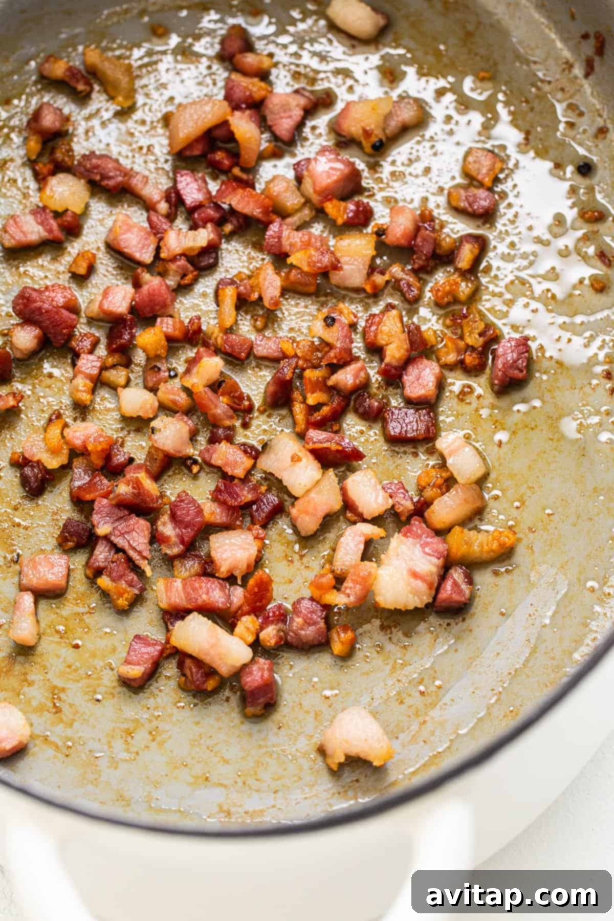 Crispy pancetta sizzling in a Dutch oven, releasing its rich aroma.