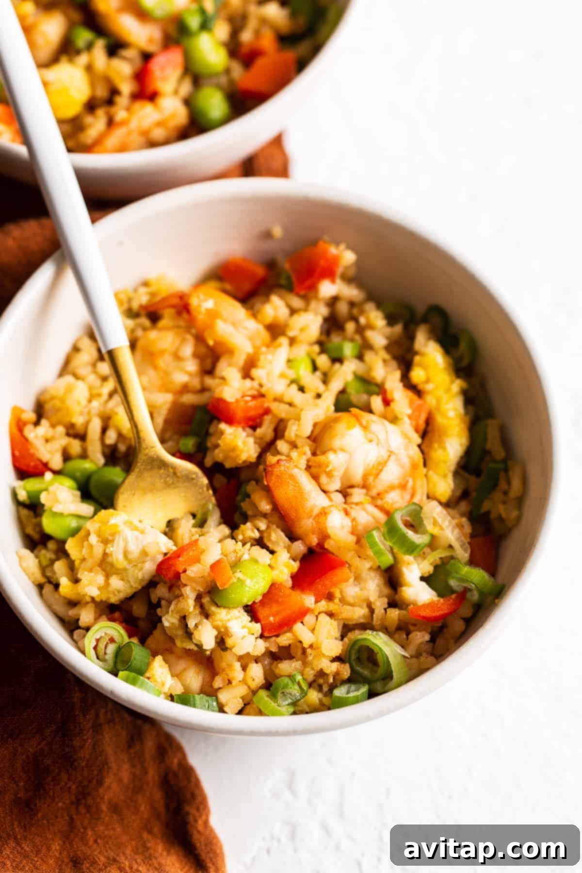 A vibrant bowl of homemade shrimp fried rice, garnished with fresh green onions and ready to be enjoyed.