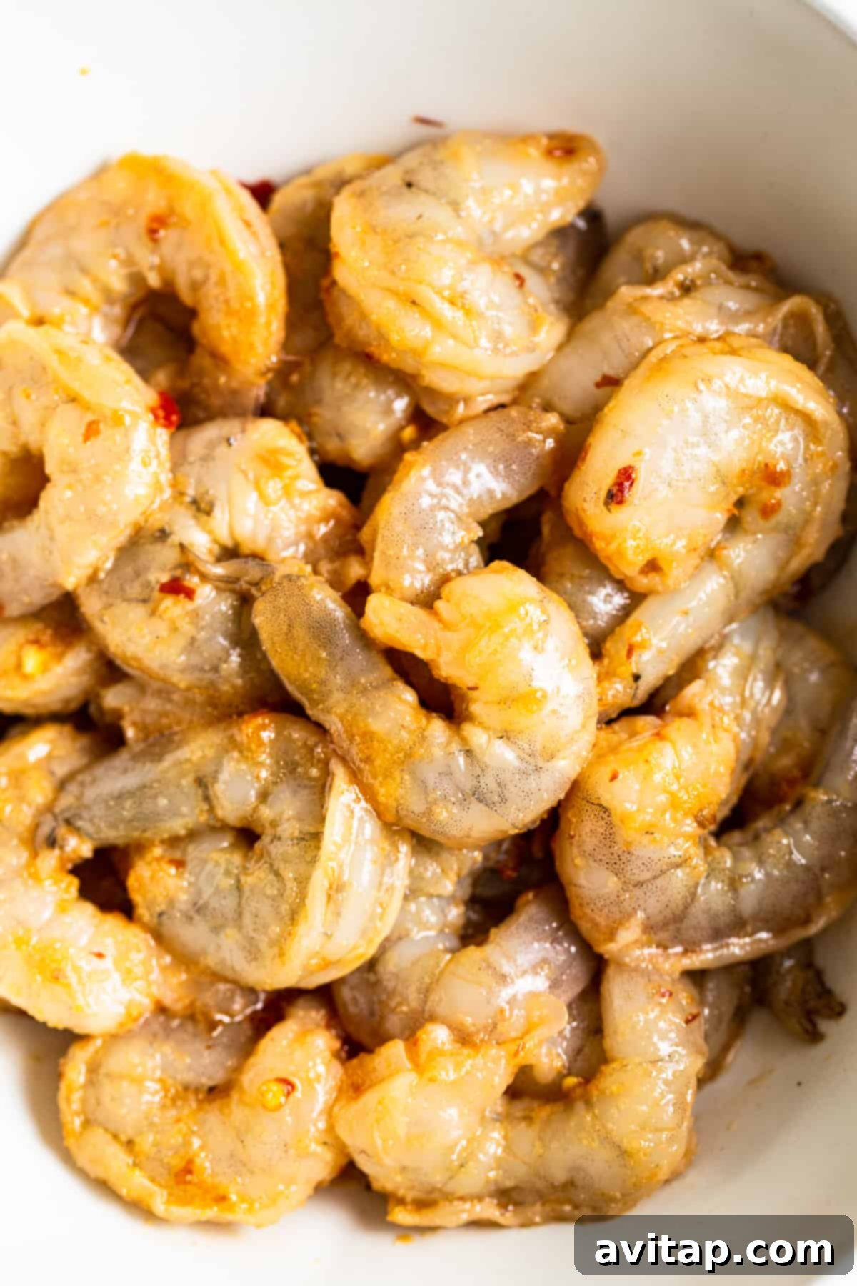 Fresh jumbo shrimp marinating in a savory sauce, ready for the fried rice preparation.
