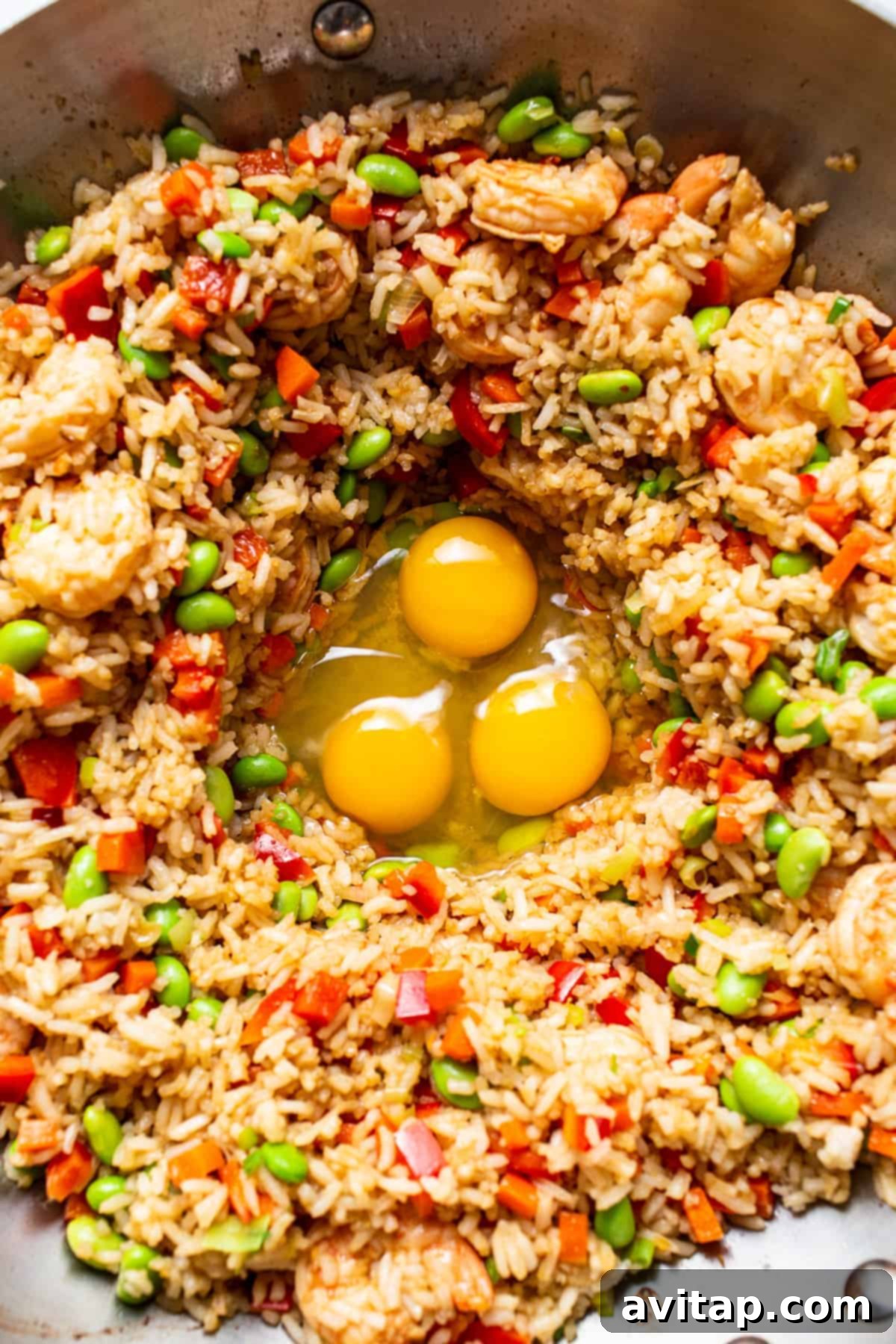 Scrambling eggs directly in the pan with the fried rice mixture, creating distinct fluffy egg pieces.
