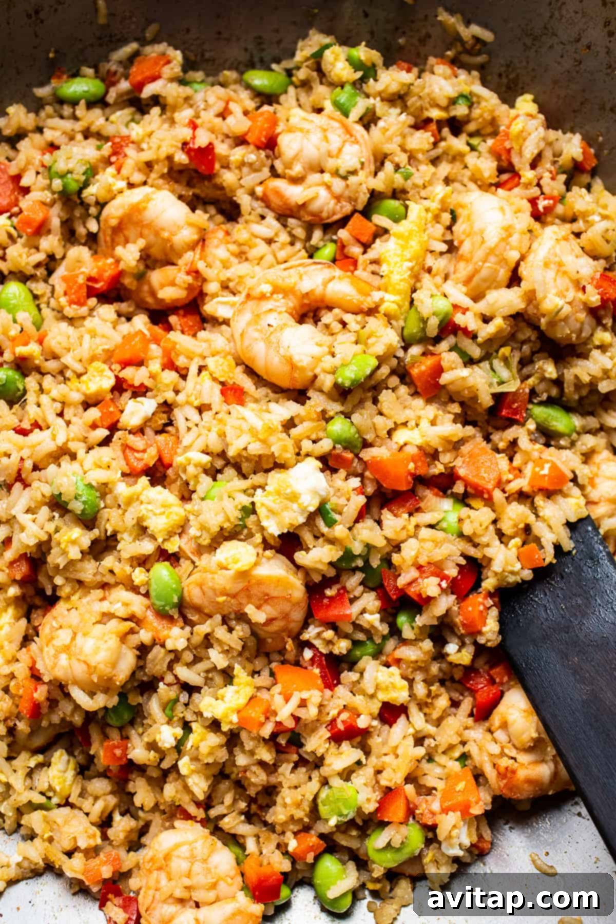 Shrimp fried rice being actively stir-fried in a large, hot skillet or wok, showcasing the vibrant colors and textures.
