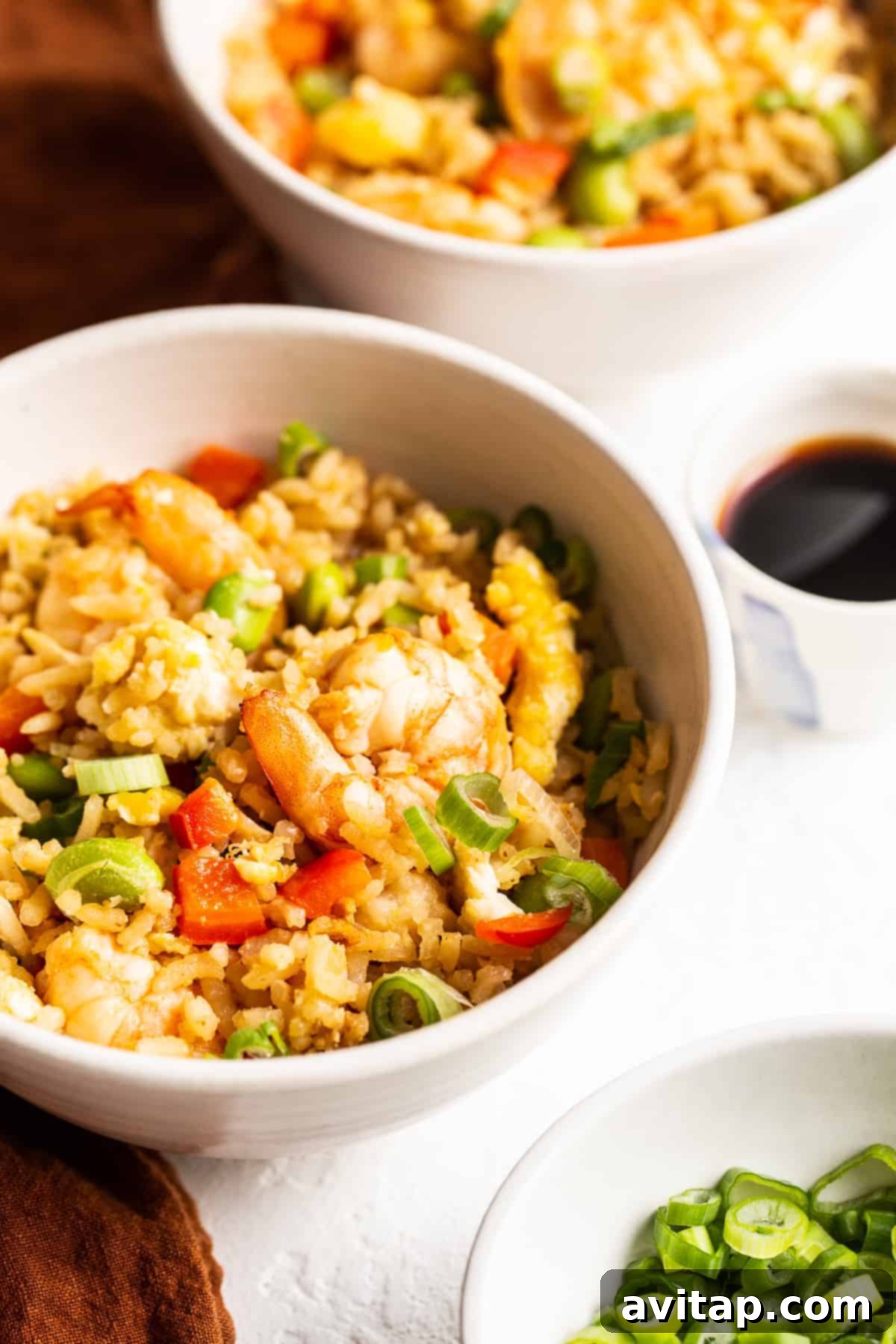 A close-up of a perfectly portioned serving of shrimp fried rice in a bowl, garnished for presentation.
