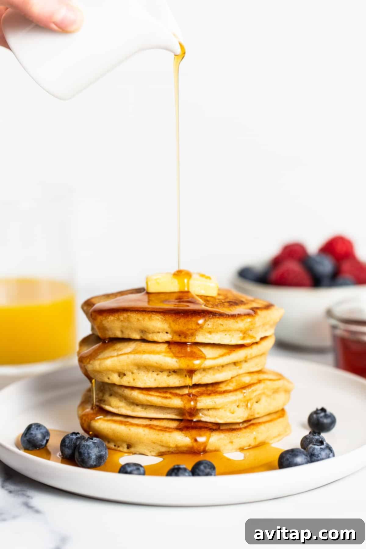 Stack of golden brown fluffy pancakes with syrup drizzled over them, ready to be served for breakfast