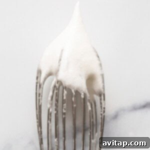 Stiff egg whites on a whisk, ready for the next step in making fluffy pancakes