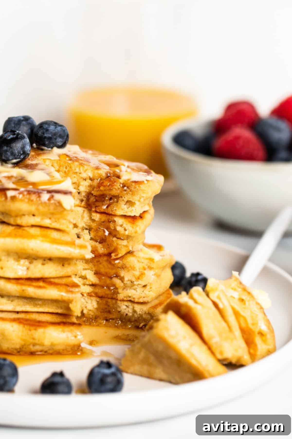 A fork piercing a fluffy brown butter pancake, revealing its airy and light interior texture