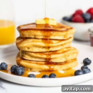 Stack of fluffy brown butter pancakes with maple syrup drizzled on top