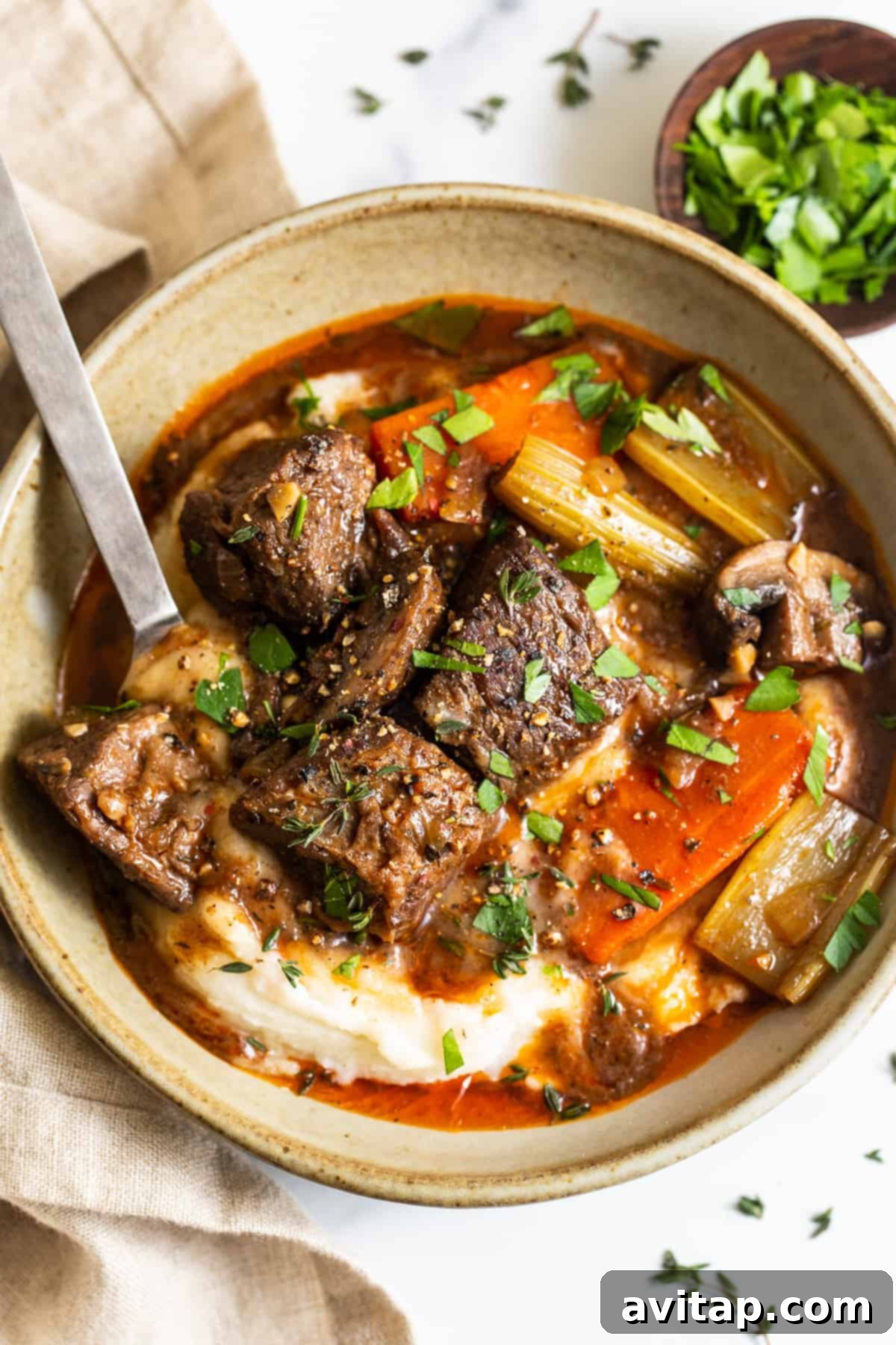 A bowl of Guinness stew served over mashed potatoes, showcasing tender beef and vegetables.