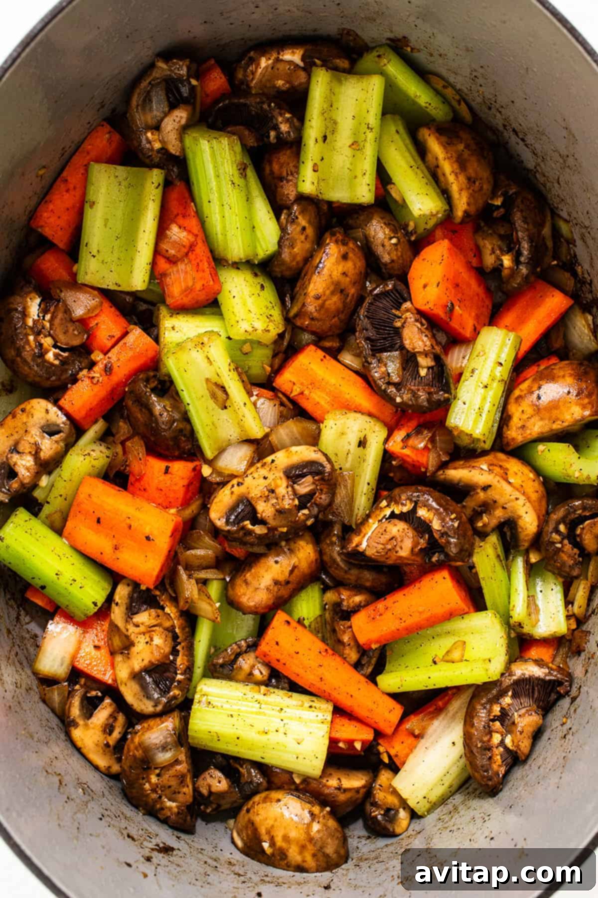 Chopped carrots, celery, and mushrooms sautéing in a Dutch oven.