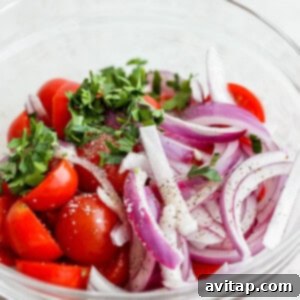 Tomatoes, onion, and parsley tossed with vinaigrette in a bowl.