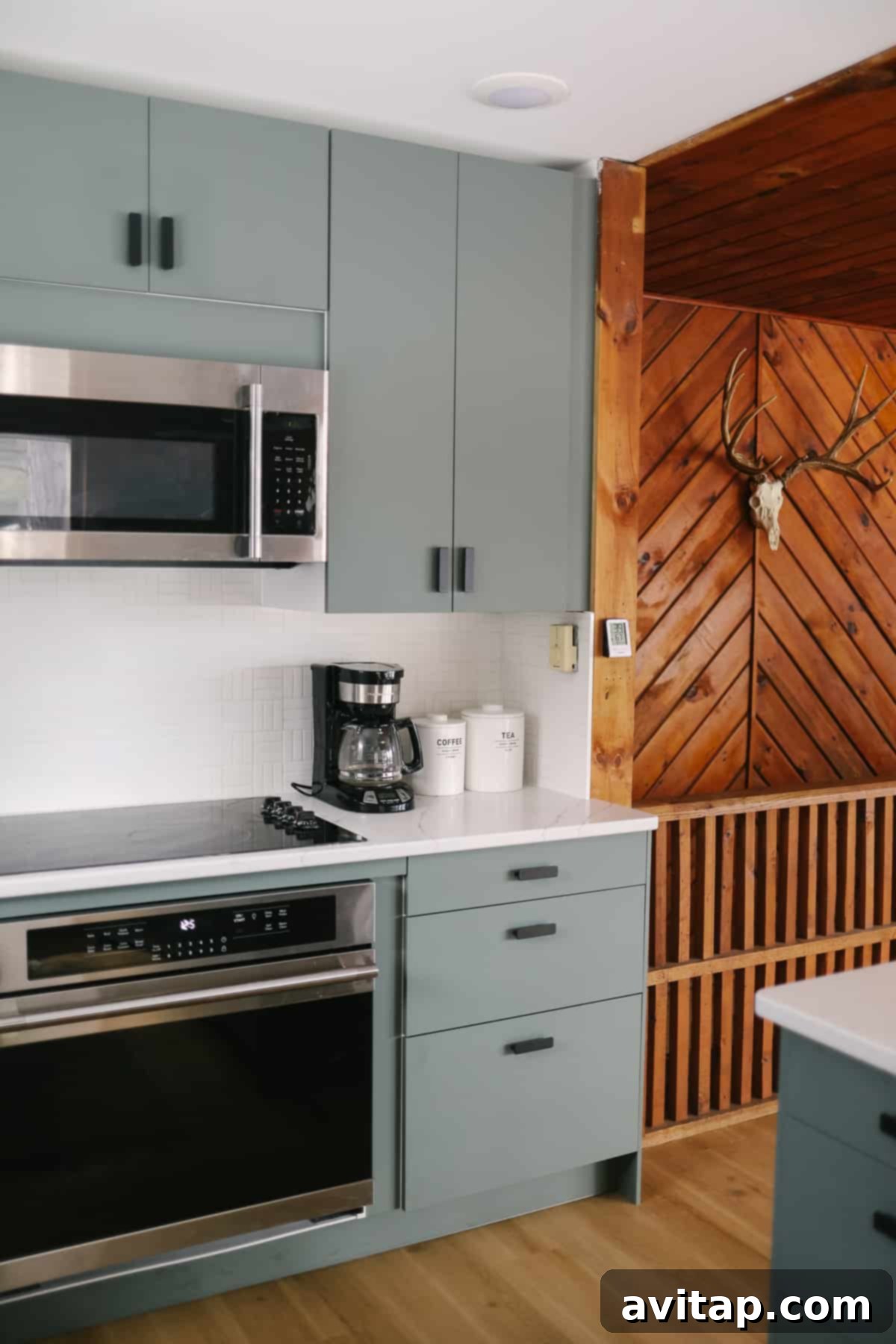 Green/grey IKEA kitchen featuring flat-panel BODARP cabinets and matte black Hackas pulls, blending Scandinavian modern style with rustic cabin elements.