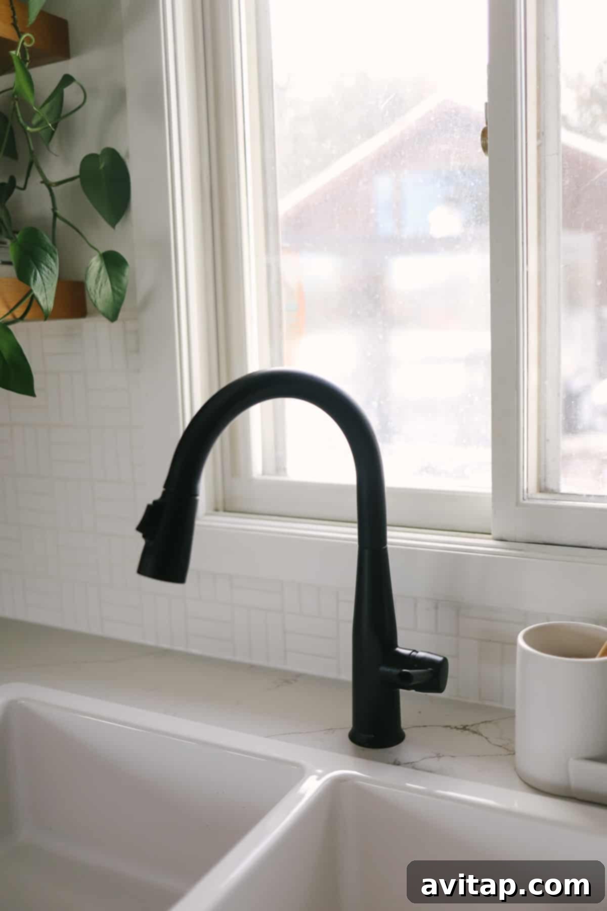 Stylish matte black Delta Essa faucet over a white Havsen farmhouse sink, adding a modern touch to the cabin kitchen.
