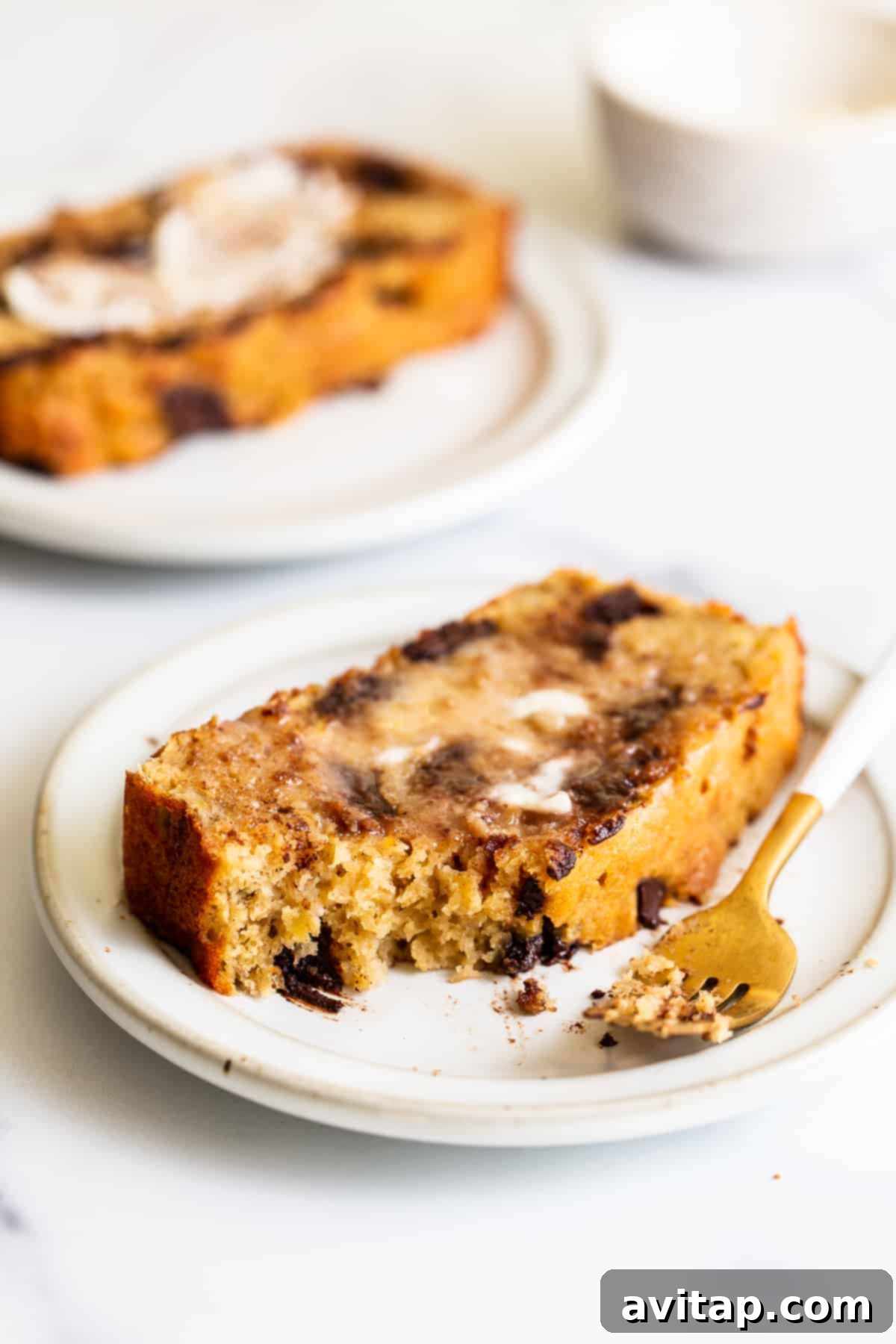 A close-up shot of a single slice of incredibly moist banana bread, showing its delightful, tender texture and golden-brown crust, ready to be enjoyed.