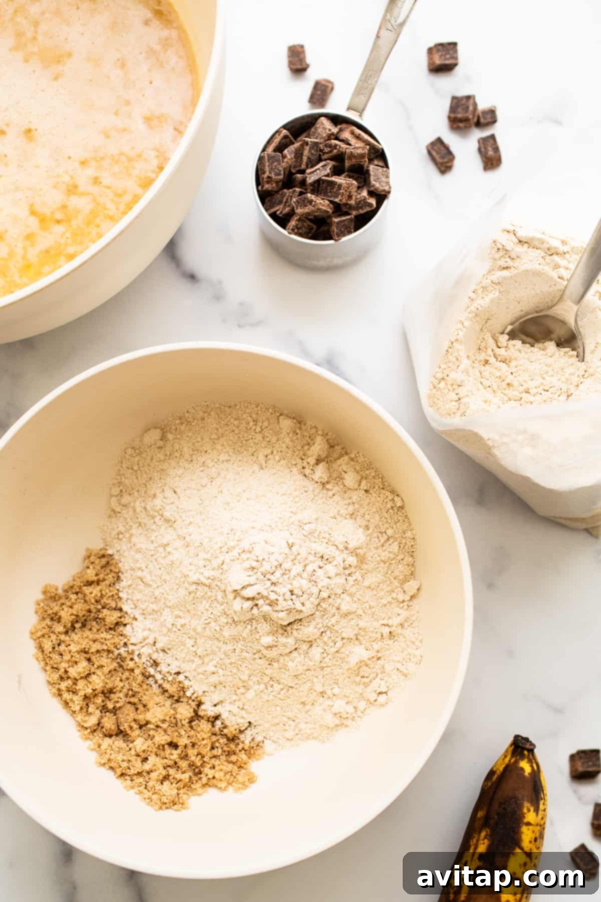 Fresh ingredients laid out on a clean kitchen counter, including ripe bananas, a box of Kodiak Cakes pancake mix, farm-fresh eggs, and golden maple syrup, ready for baking this easy banana bread.