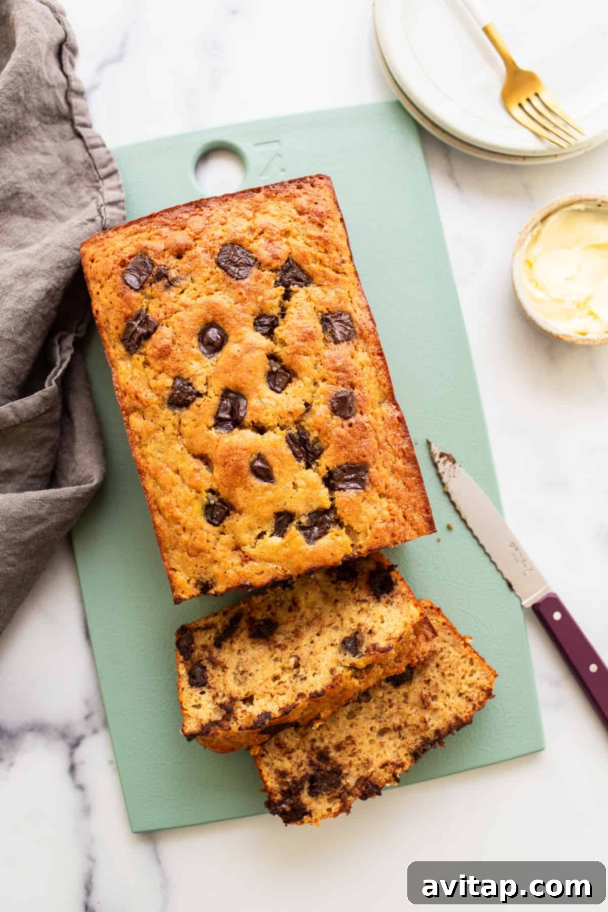 Beautifully sliced banana bread, showcasing its incredibly moist texture and perfectly melted dark chocolate chips distributed throughout the loaf.
