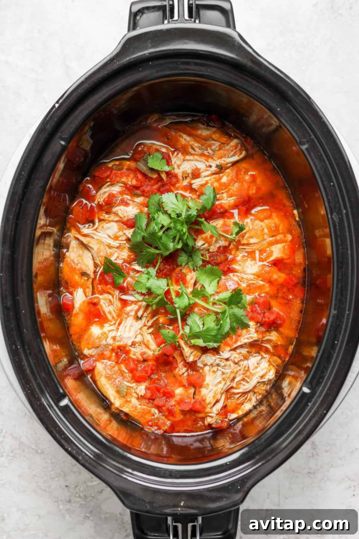 Shredded chicken taco meat with fresh cilantro, ready to serve from the slow cooker.