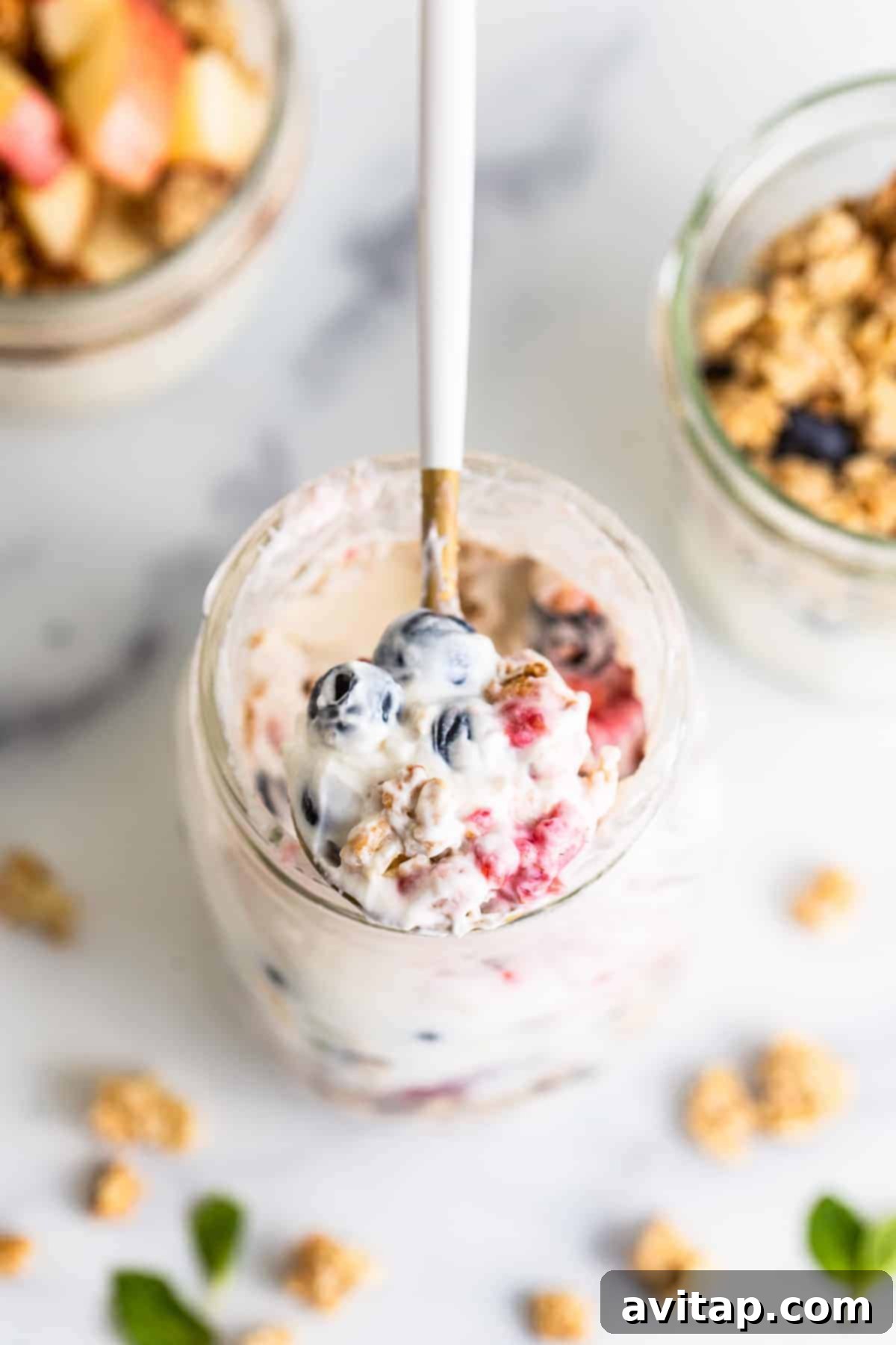 A spoonful of yogurt parfait showing layers of fruit, yogurt, and granola