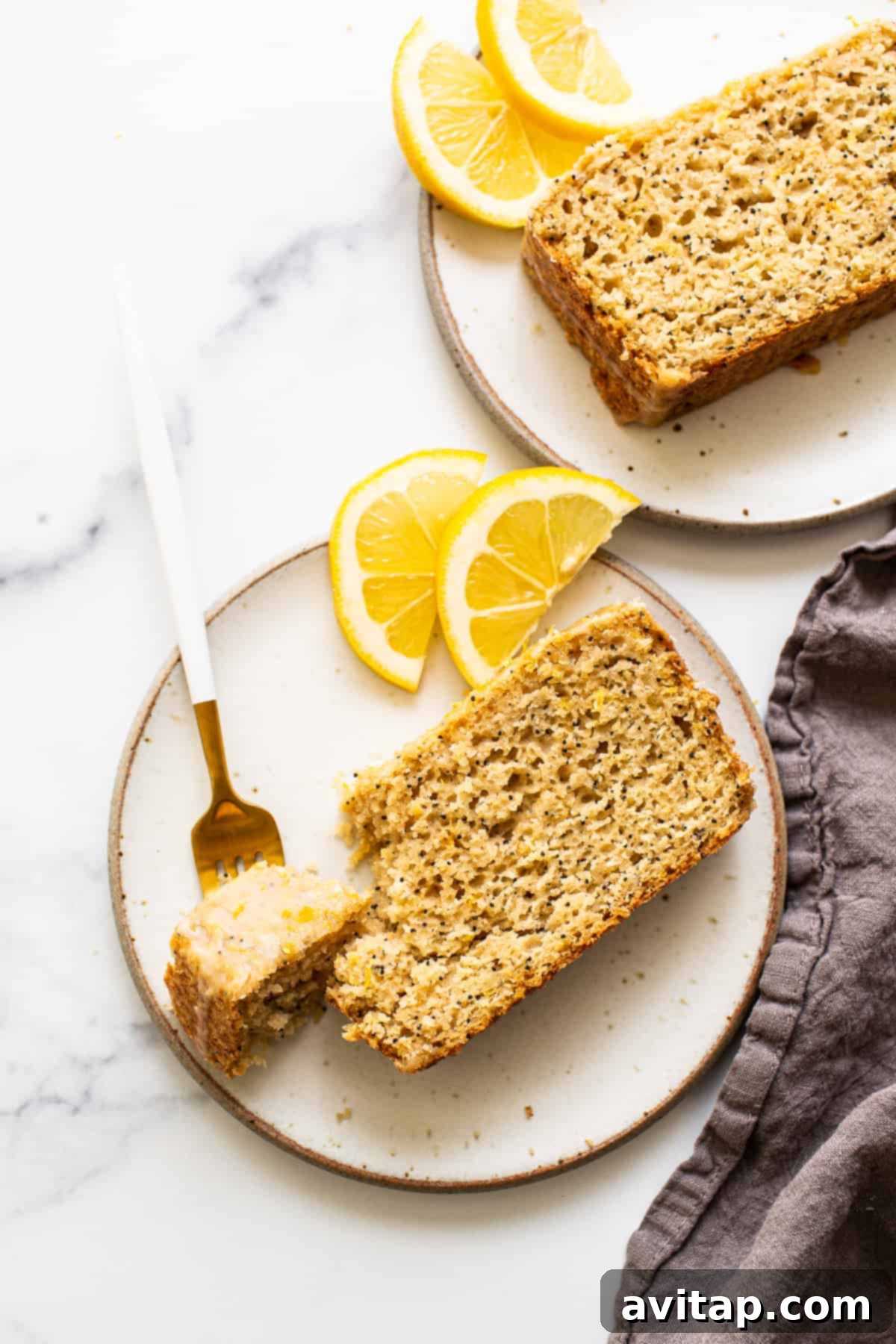 A single slice of lemon poppy seed bread with glaze on a white plate, ready to be enjoyed with a cup of coffee.