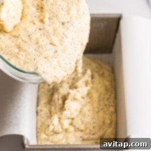 Pouring the lemon poppy seed bread batter into a parchment-lined loaf pan.