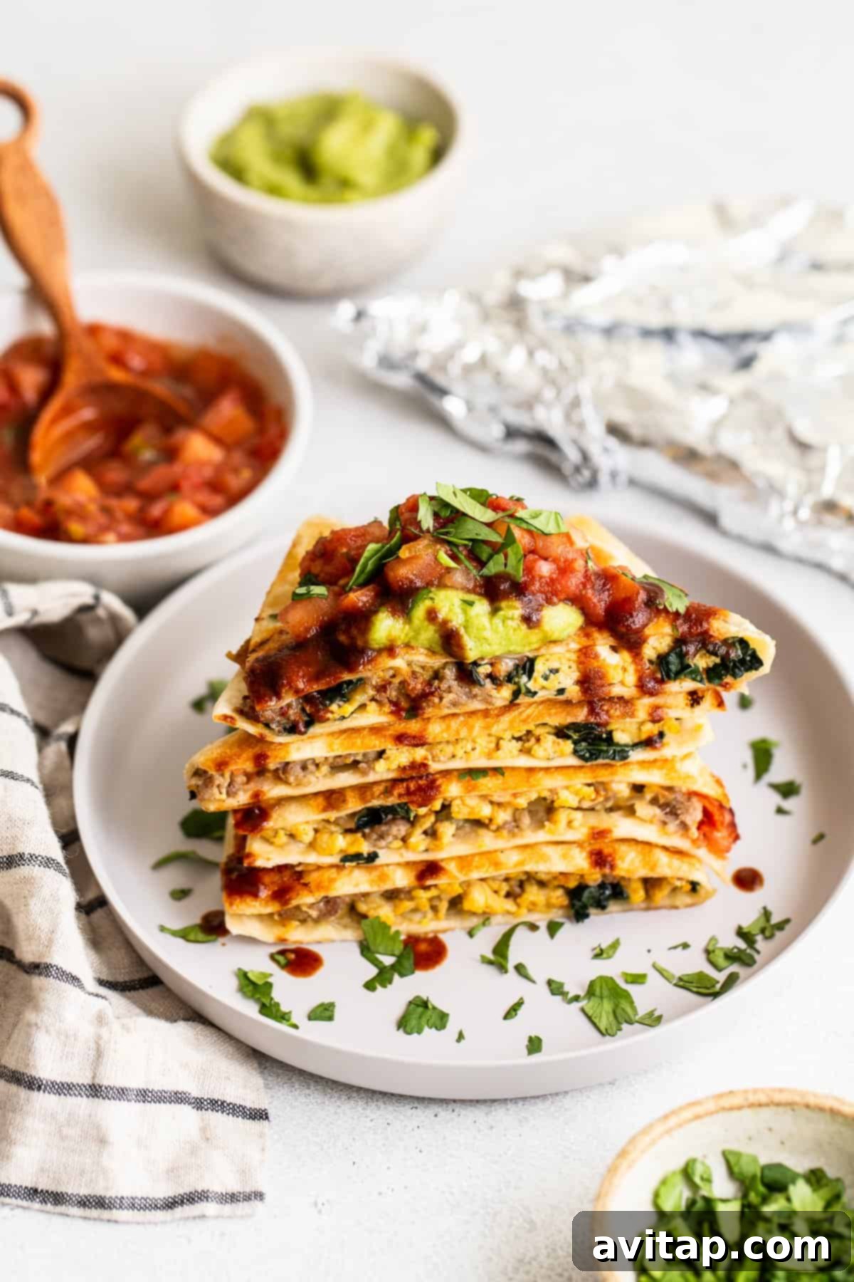 Delicious breakfast quesadillas served with vibrant toppings. Breakfast quesadilla slices elegantly presented on a plate, garnished with fresh salsa and creamy guacamole.