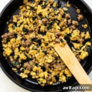 Your Go-To Freezer Breakfast Quesadillas 3 Fluffy scrambled eggs cooking in a skillet, stirred with a wooden spatula for the breakfast quesadilla filling.