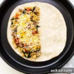 Your Go-To Freezer Breakfast Quesadillas 4 A breakfast quesadilla taking shape in a vibrant green skillet, filled with savory ingredients.
