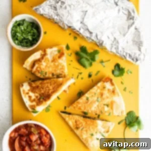 Your Go-To Freezer Breakfast Quesadillas 5 Freshly cooked quesadillas and a bowl of creamy guacamole on a rustic yellow cutting board, ready for serving.