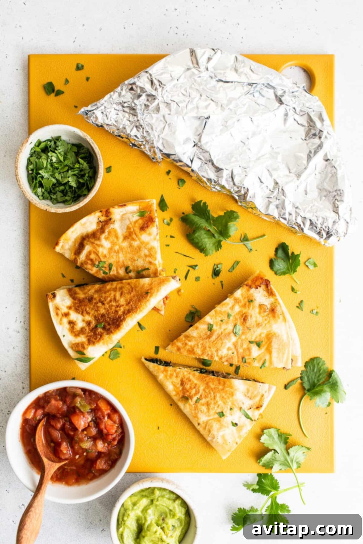 Serving sliced make-ahead breakfast quesadillas. Freshly made breakfast quesadillas, sliced and arranged on a wooden cutting board.