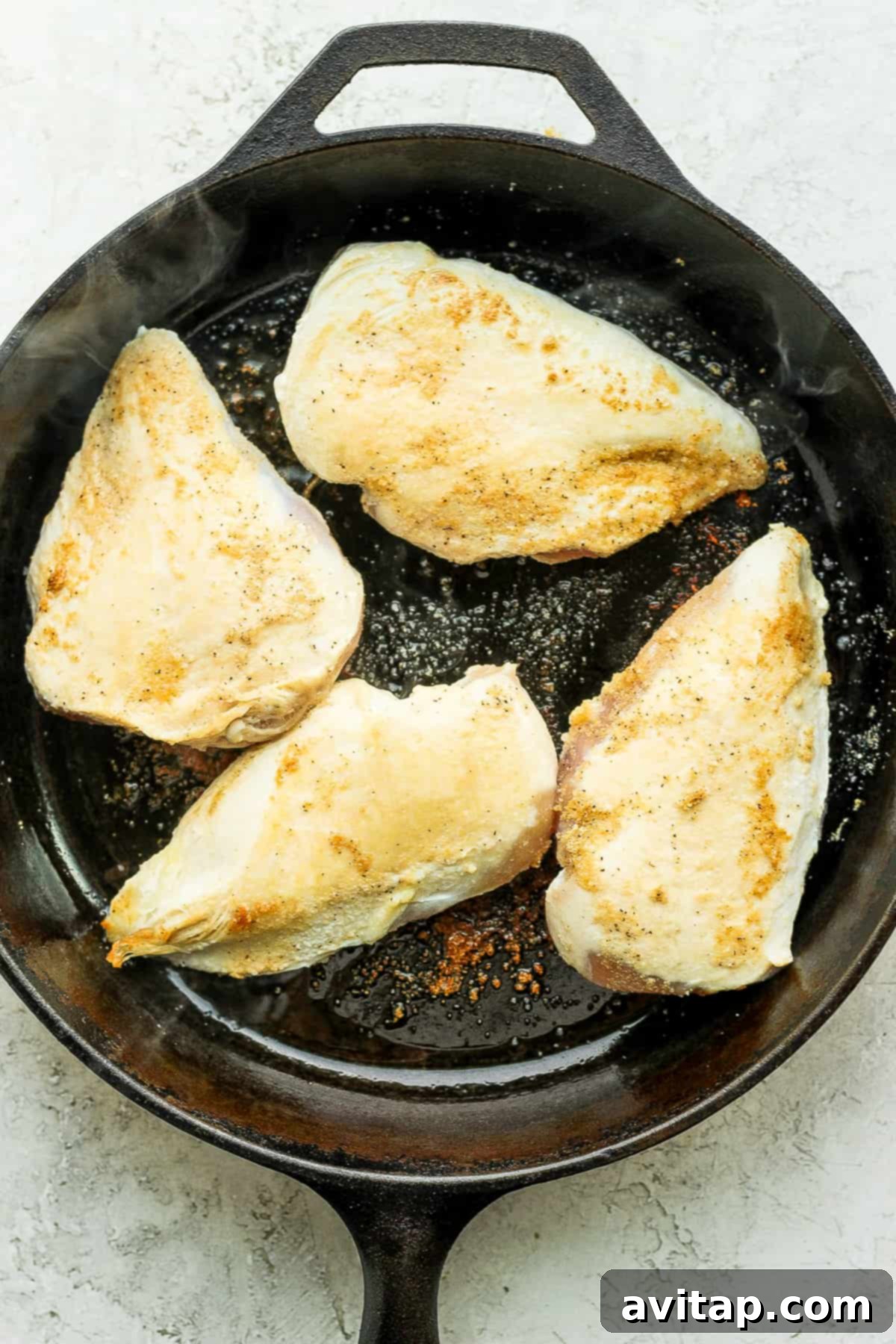 Searing chicken breasts in a hot skillet for the tinga recipe.