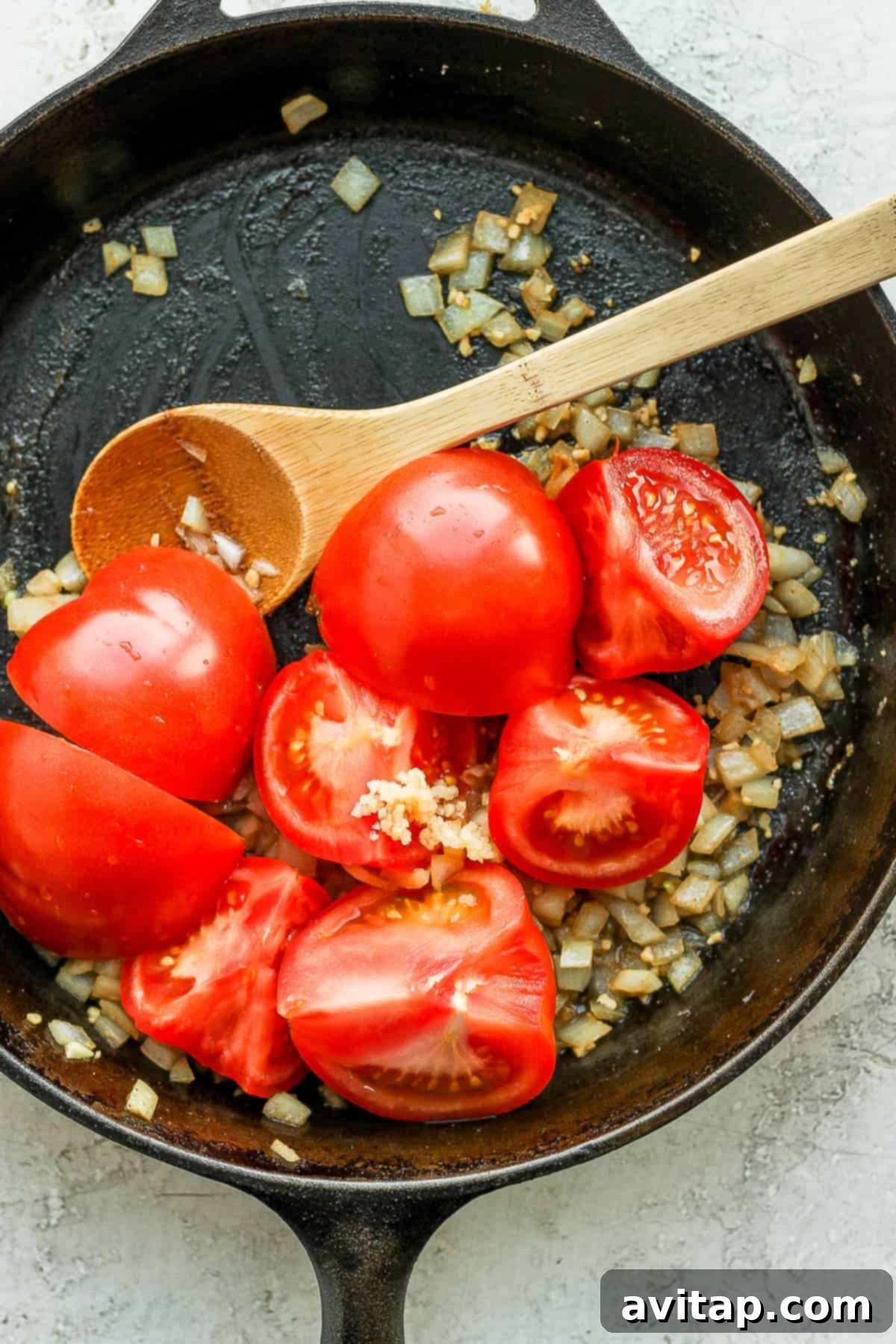 Sautéed onions, garlic, and tomatoes forming the flavorful base in a pan.