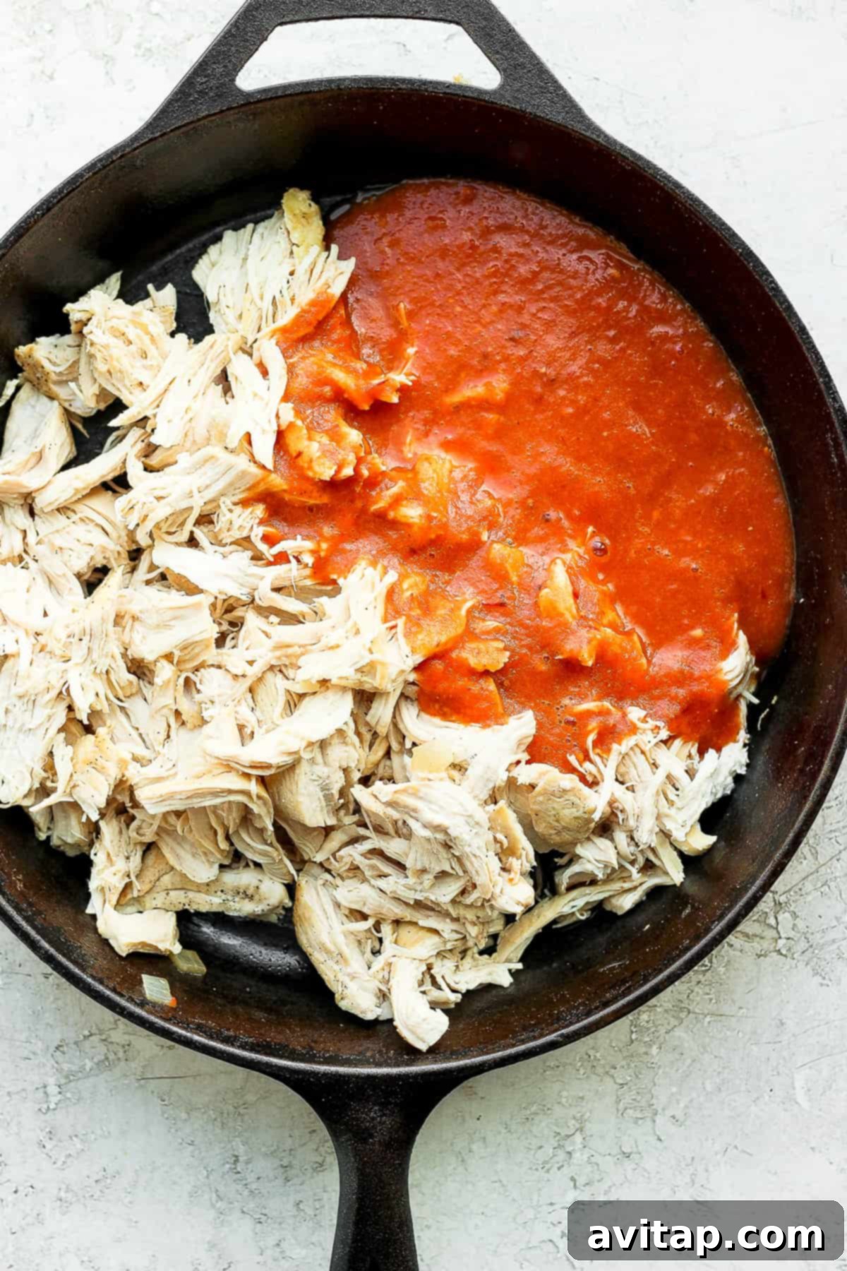 Rich, saucy Chicken Tinga simmering in a cast iron skillet, ready to be served.