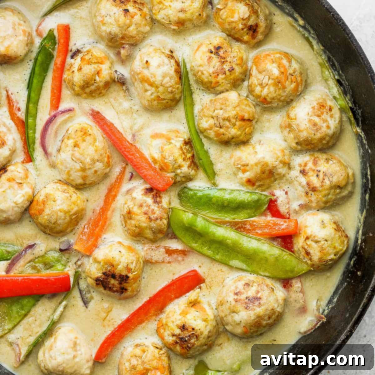 Vibrant Green Curry Chicken Meatballs 2 Chicken meatballs and vibrant vegetables simmering in a cast iron pan, ready to be served as a delicious green curry meal.
